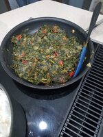 A spatula and cooked spinach in a cooking pan